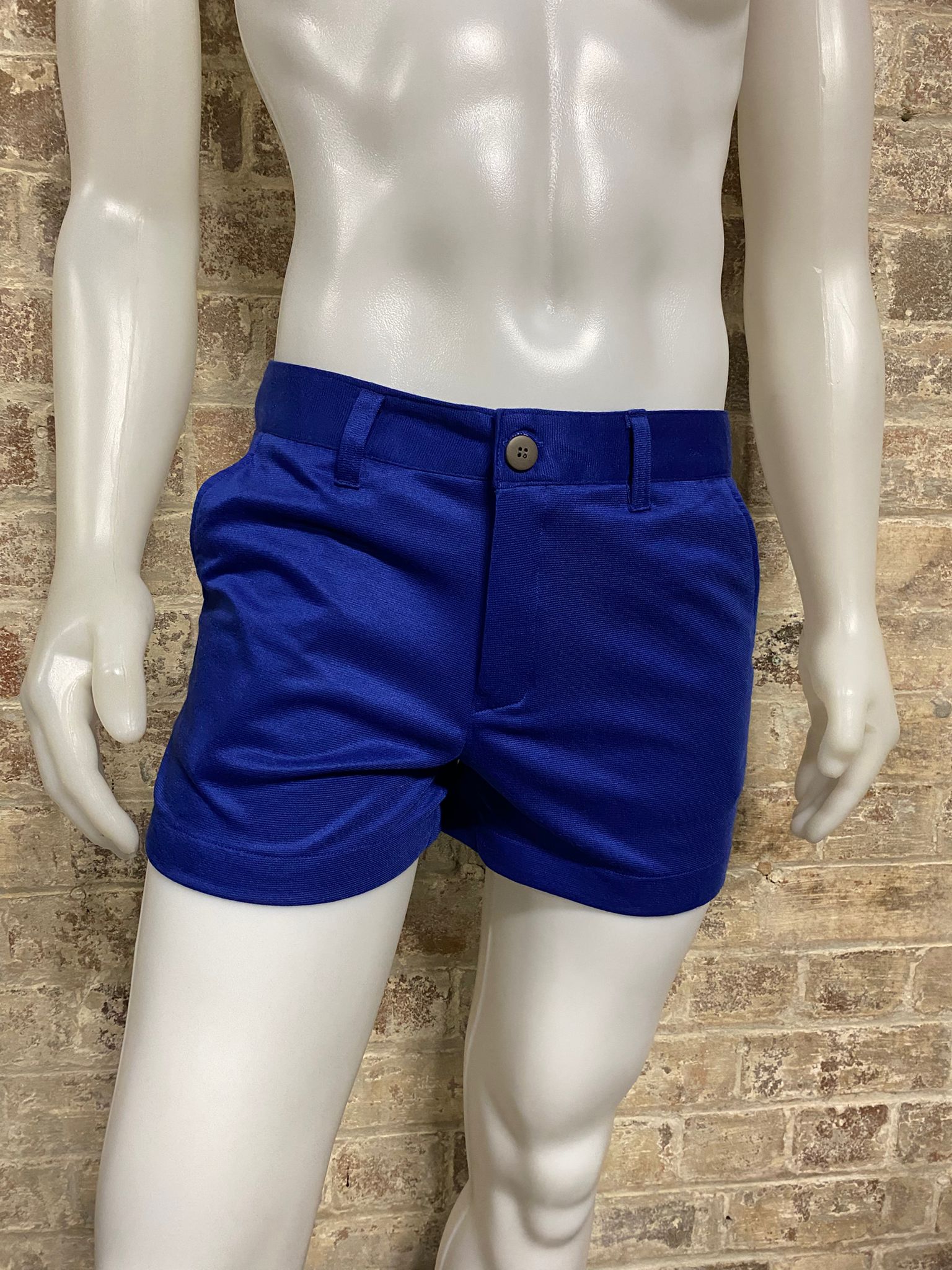 Mannequin wearing blue shorts against a brick wall background