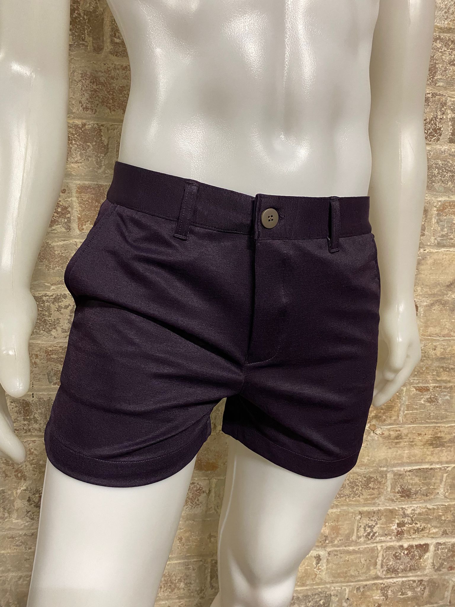 Purple shorts on a mannequin against a brick wall background