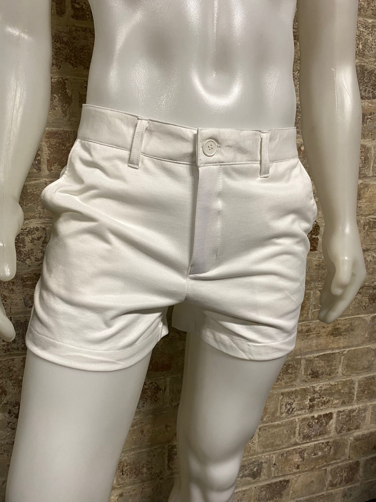 White shorts on a mannequin against a brick wall.